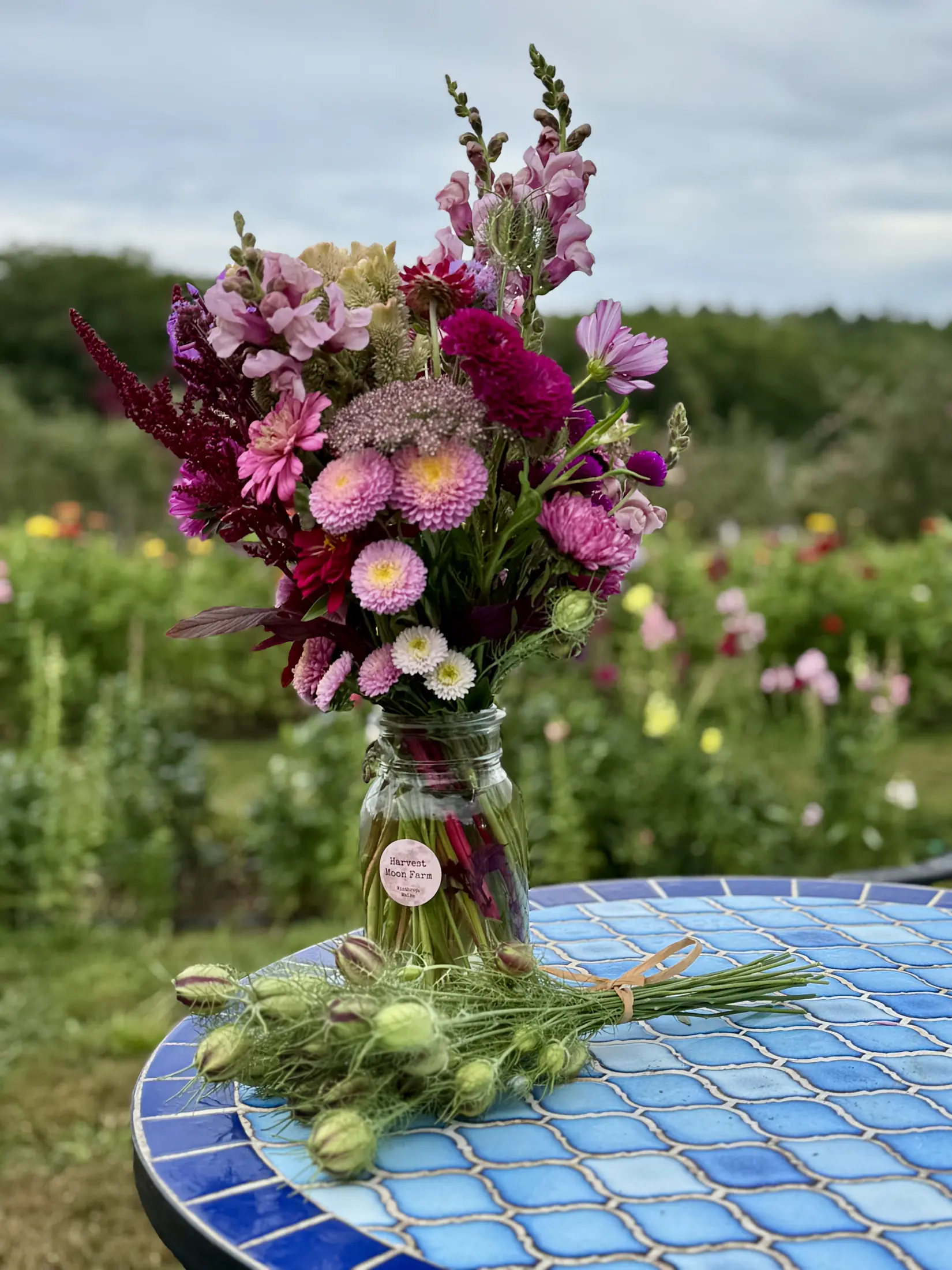 A cut bouquet in a mason jar beside the flower field